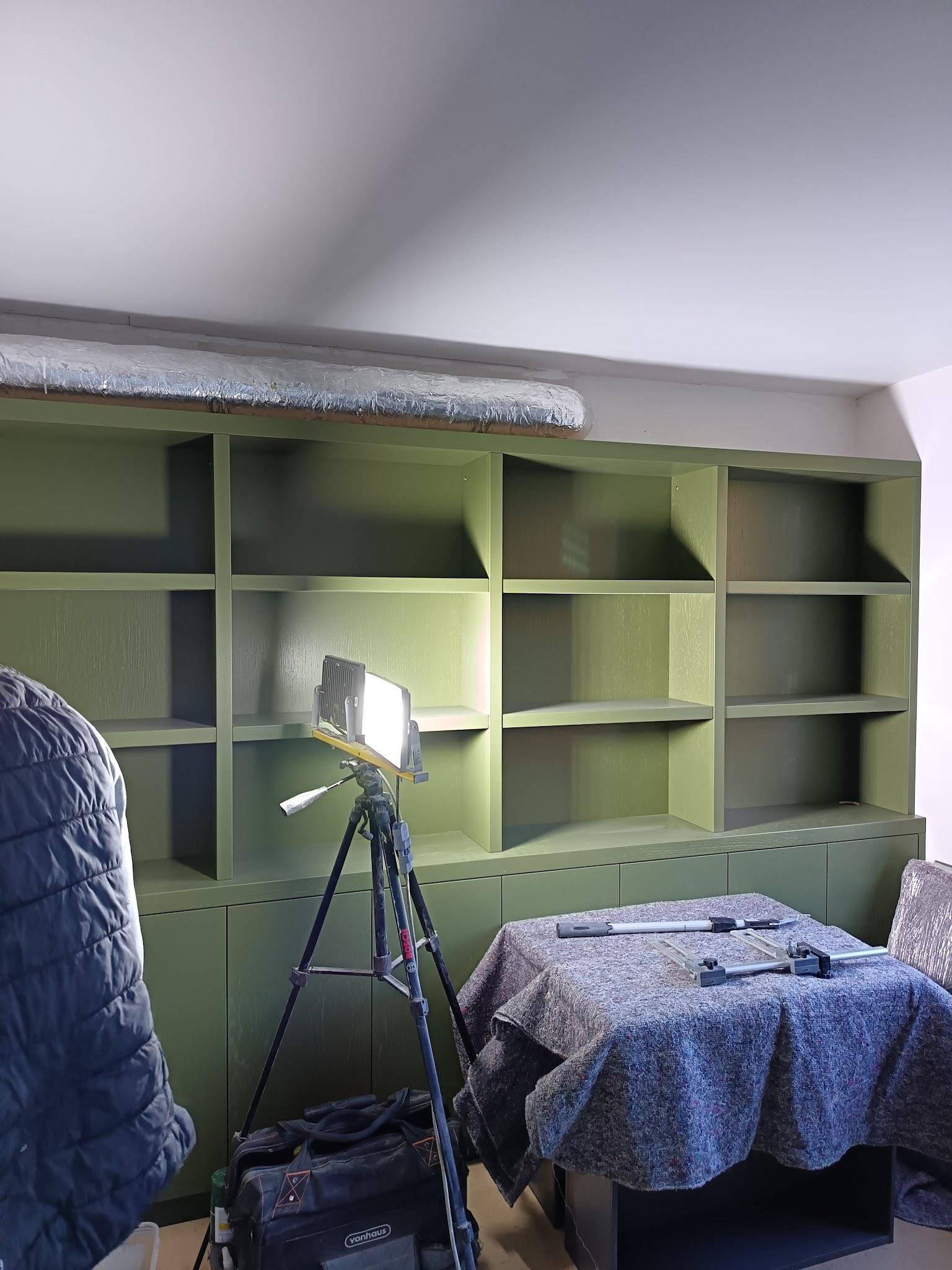 Bespoke green shelving unit during installation by our London carpenters